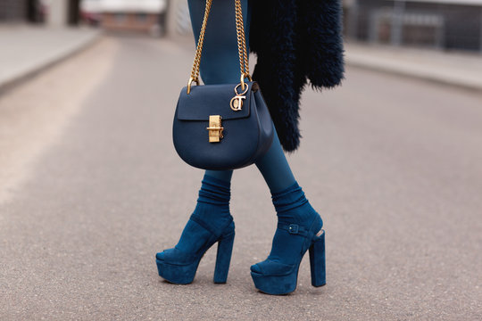 Street, bright style. A young girl in a blue fur coat with a handbag in heels. Details.