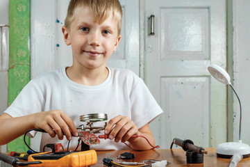 The child remotiruet microcircuit. Workplace with soldering iron, microcircuit, magnifying glass,...