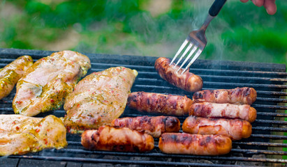 Assorted mixed grill from chicken meat, and pork, sausages  roasting on barbecue grid cooked for summer family dinner