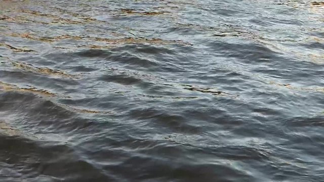 Cold water of wide northern river. Dark surface with small waves and some sun flares. Natural background. Somewhere in Russia.