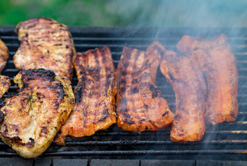 Assorted mixed grill from chicken meat, and pork, sausages  roasting on barbecue grid cooked for summer family dinner