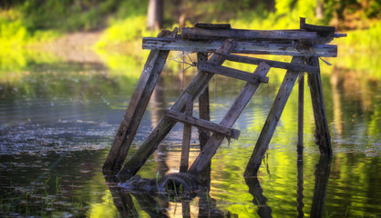 Old wooden fishing platform on the lake with clear water. The platform is made of old window frames