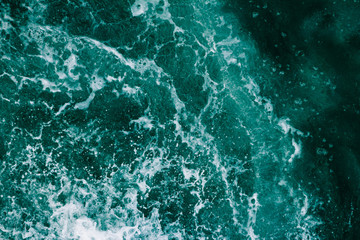 Fototapeta na wymiar Surface of the sea with waves, splash, foam and bubbles at high tide and surf, green abstract background