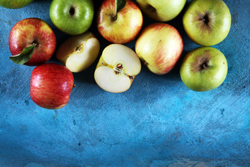 Ripe red apples with leaves on wooden background.