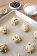 Uncooked chocolate chip cookie dough balls on parchment paper