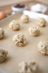 Close up on a grid of chocolate chip cookie dough balls on parchment paper
