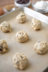 Side view on a grid of chocolate chip cookie dough balls on parchment paper
