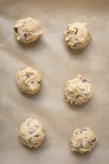 Top down close up on a grid of chocolate chip cookie dough balls on parchment paper