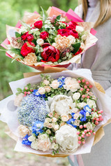 Young girl holding two a beautiful spring bouquets. flower arrangement with hydrangea and peonies. Color light blue and red. The concept of a flower shop, a small family business
