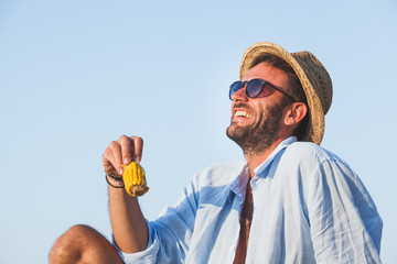 Young man eating corn on the beach © marjan4782