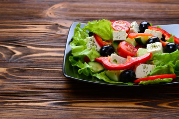 Greek salad on a wooden background. Space for text or design.