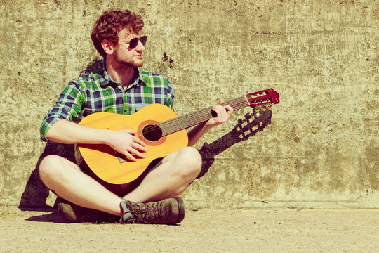Young bearded hipster man with guitar outdoor