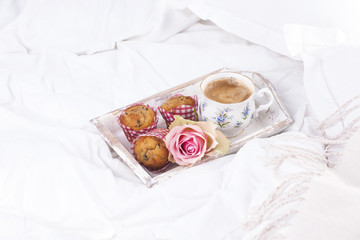 Fototapeta na wymiar white bed, fresh coffee, breakfast cakes and a bouquet of pink roses. Good morning Vintage photo.