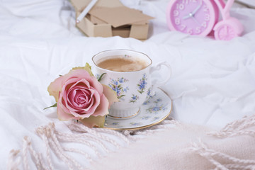 Pink alarm clock, white bed, fragrant coffee and pink roses. Good morning Vintage photo. Copy space.