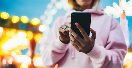 Front view girl pointing finger on screen smartphone on defocus background bokeh light in evening street, woman using in hands mobile phone gadget in night city, online wifi internet concept