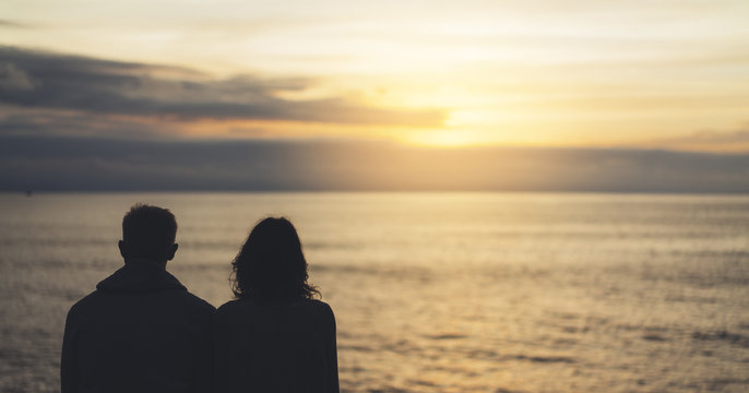 Couple hugging on background beach ocean sunrise, meeting of lovers concept, silhouette two romantic people cuddling and looking on view evening seascape, hipster enjoy sunset together