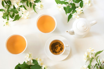 Green jasmin tea and jasmine flowers, cup of green tea on white. Top view. Teatime.