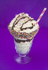 Milkshake with Sprinkles Around the Rim on a Purple Background