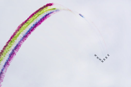 Airplanes on airshow with colorful multicolored trails of smoke against a blue sky. Aircraft, flying display and aerobatic show