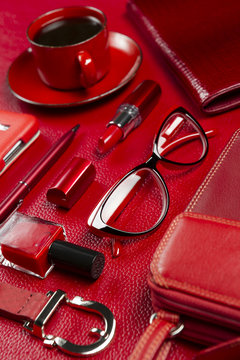 Red woman accessories with coffee, cosmetic, gadget, jewelry and other luxury objects on leather background, fashion industry, modern female concept, selective focus 
