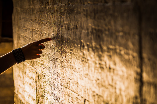 Woman hand pointing ancient script on a wall carving at an Indian temple