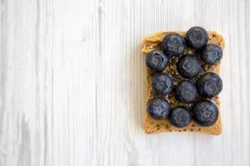 Toast with peanut butter, blueberries and chia seeds on a white wooden background, top view. Healthy dieting.