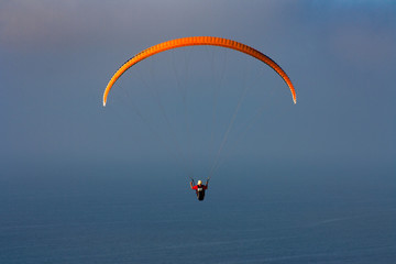 Orange Para-glider over the ocean