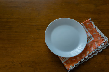 Empty plate on wooden tabletop with tablecloth