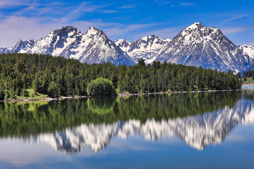 The Grand Tetons of Wyoming are reflected perfectly in the still waters of Jackson Lake