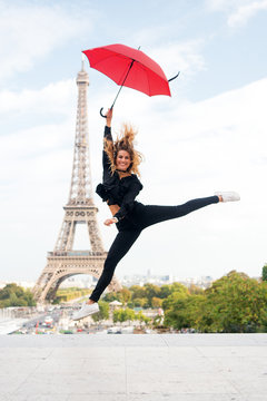 Lady with umbrella excited about visiting Eiffel Tower, sky background. Dreams come true concept. Lady tourist sporty and active in Paris city center jumps up. Girl tourist enjoy walk and sightseeing