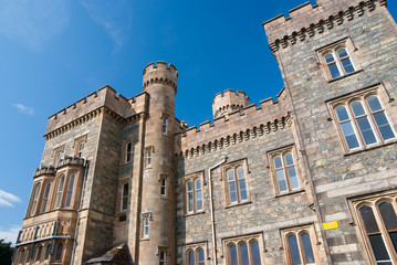 Fototapeta na wymiar Castle building with towers on sunny blue sky. Lews Castle in Stornoway, United Kingdom. Historic architecture and design. Landmark and attraction. Summer vacation and wanderlust