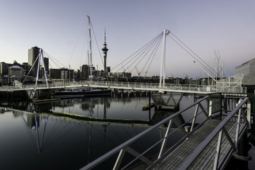 Auckland skyline seen from Viaduct Harbour over the pedestrian bridge, at dawn. Auckland, New Zealand.