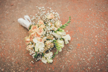 beautiful wedding bouquet with two golden rings on the floor