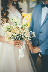 bride and groom staying together with bouquet in hands