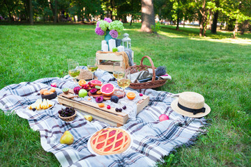 Picnic background with white wine and summer fruits on green grass, summertime party