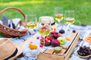 Obraz na płótnie Canvas Picnic background with white wine and summer fruits on green grass, summertime party