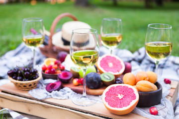 Fototapeta na wymiar Picnic background with white wine and summer fruits on green grass, summertime party