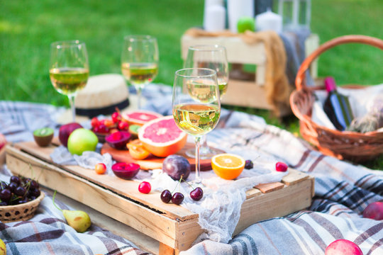 Picnic background with white wine and summer fruits on green grass, summertime party
