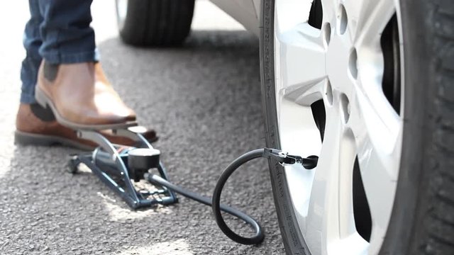 Close Up Of Man Inflating Car Tyre With Foot Pump