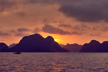 Naklejka na ściany i meble Halong bay boats, Vietnam Panoramic view of sunset in Halong Bay, Vietnam, Southeast Asia,UNESCO World Heritage Site, Poor lighting conditions