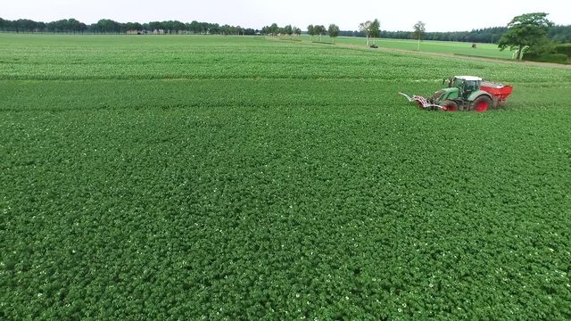 Tractor drives past crops on farmland, aerial