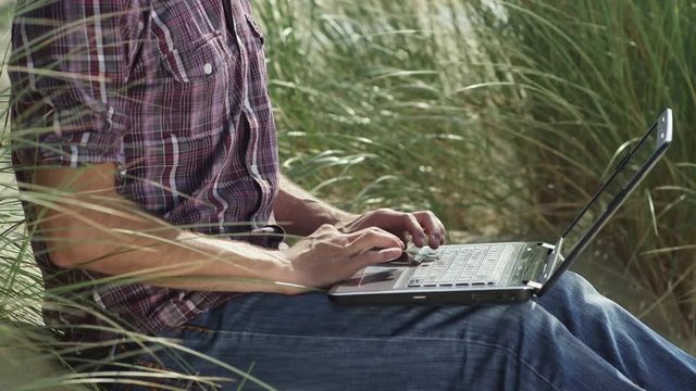 Person sues laptop in field, close up