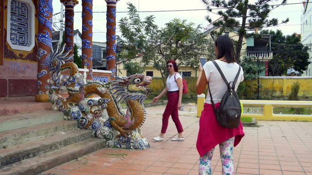 Women are photographed with a dragon statue