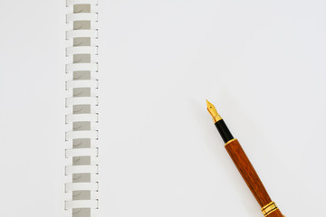 Open notebook with white blank sheets and an ink pen with a gold pen.