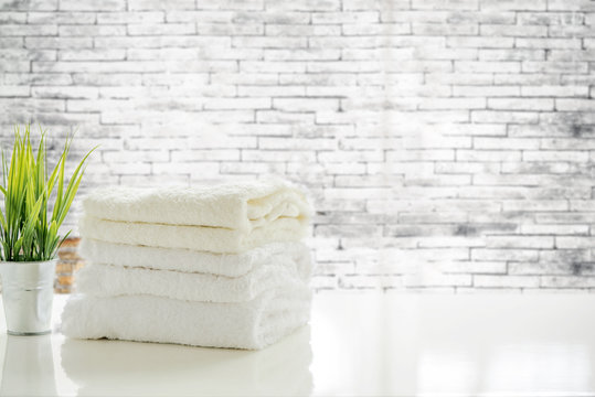 Towels on white table with copy space on blurred old brick wall background