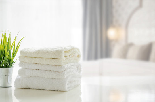 Towels on white table with copy space on blurred bedroom background