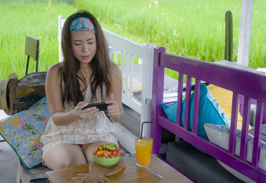 happy and pretty digital nomad Asian Korean woman taking picture of fruit salad with mobile phone for sharing on internet social media healthy nutrition