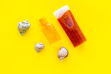 Sunscreen for sea vacation. Bottles with cream or lotion near sea shells on yellow background top view copy space