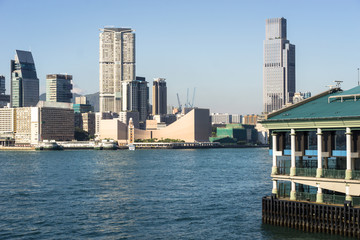 Central Star Ferry pier with the Kowloon skyline at Tsim Sha Tsui view from across the Victoria harbour in Hong Kong on a sunny day in China SAR.