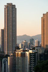Fototapeta na wymiar Sunset over tall apartment tower in Happy Valley in Hong Kong island with the peaks of kowloon in the back in Hong Kong, China
